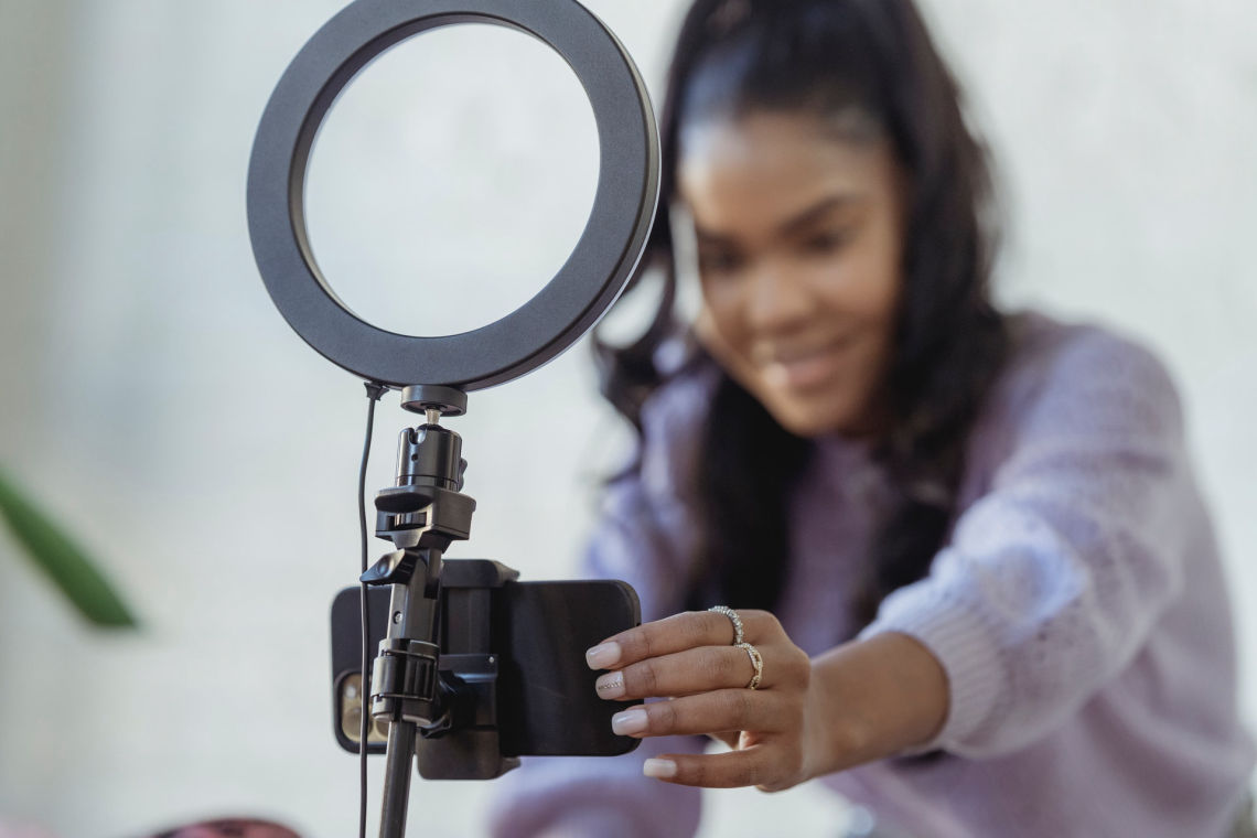 A young, black female influencer fixes her phone ready for shooting a video